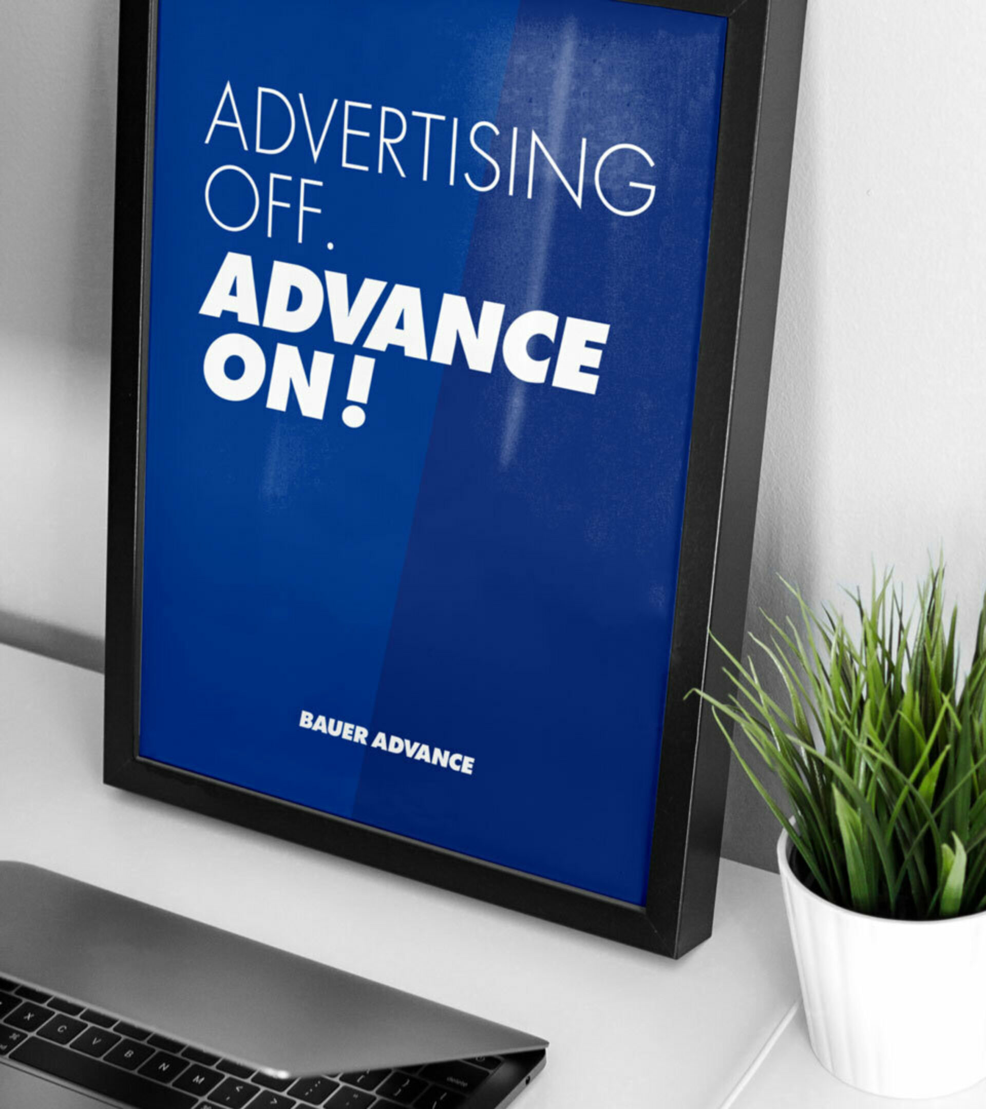 Ein dunkelblaues Poster in einem Bilderrahmen lehnt an der Wand mit weißem Text: Advertising off. Advance on!