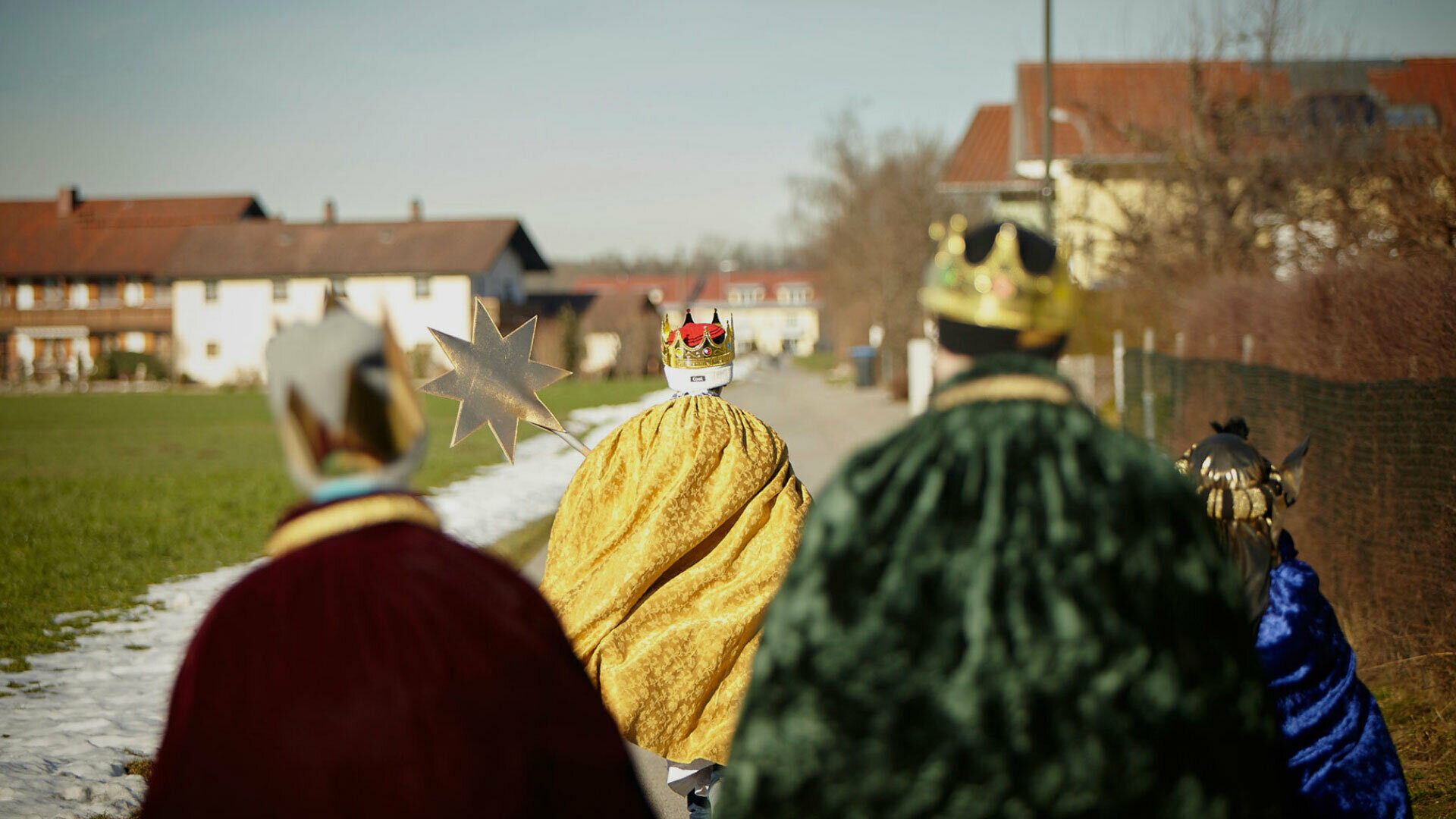 Sternsinger laufen durch ein Dorf