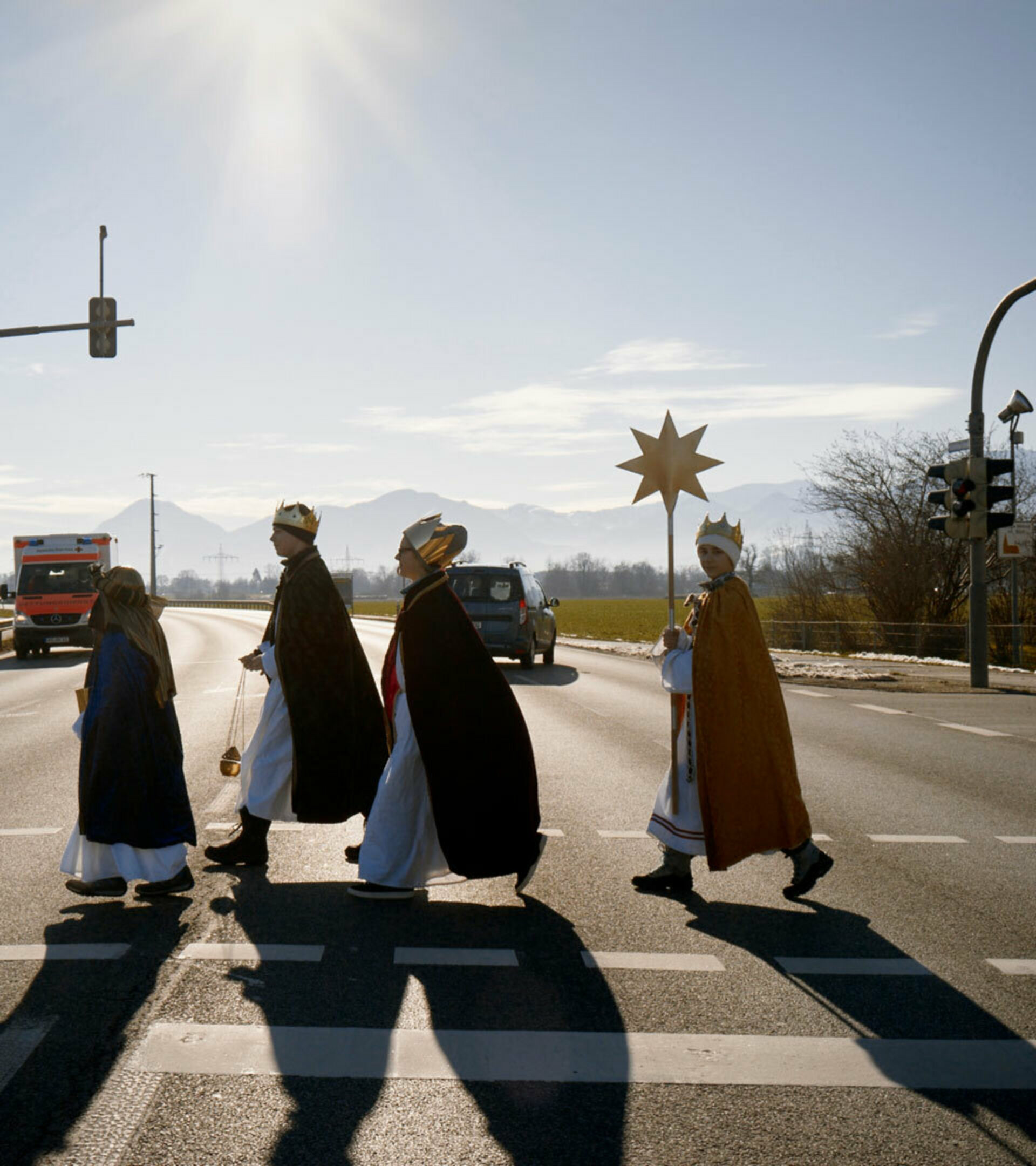 Vier Kinder in Sternsinger-Kleidung überqueren eine Straßenkreuzung